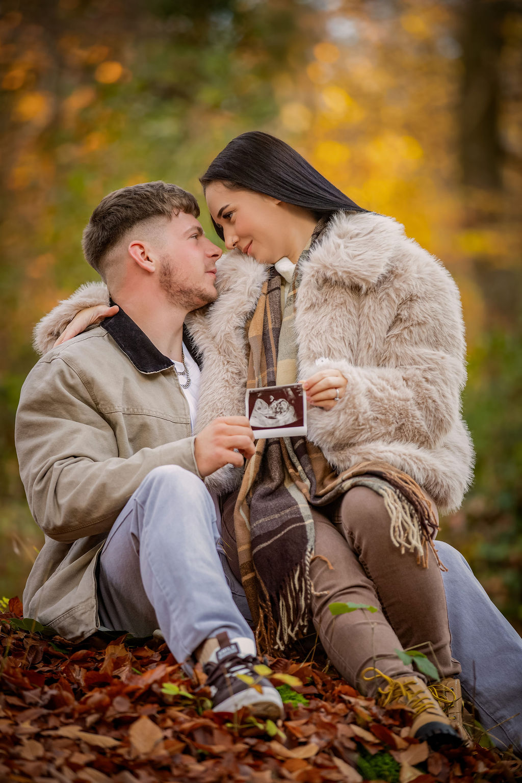 Expecting couple among autumn leaves