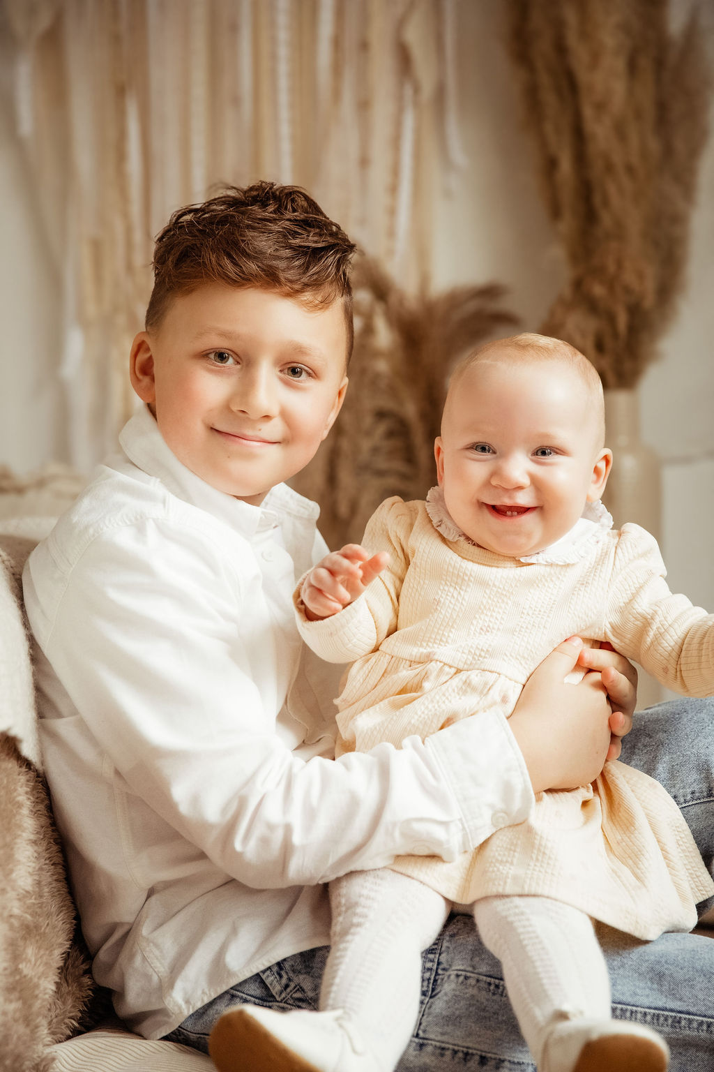 Boy holding baby sister in boho studio